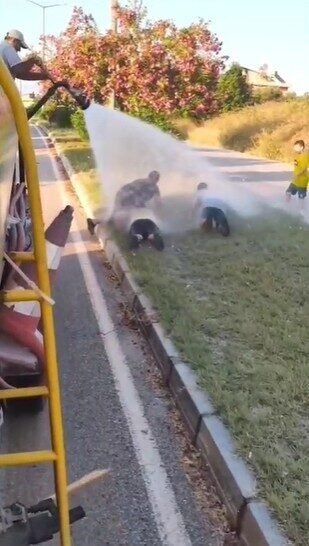 Sıcaktan bunalan çocuklar refüjde sulama yapan su tankeriyle serinledi