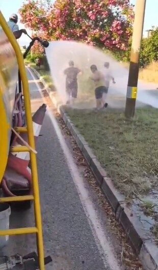 Sıcaktan bunalan çocuklar refüjde sulama yapan su tankeriyle serinledi