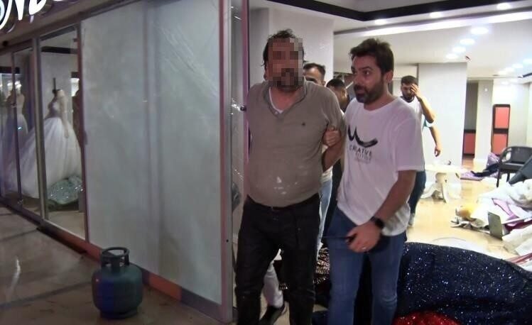 Eşinin mağazasına girip gelinliklerin üzerlerine kolonya döktü, tüpe çakmağı dayayınca tazyikli suyu yedi